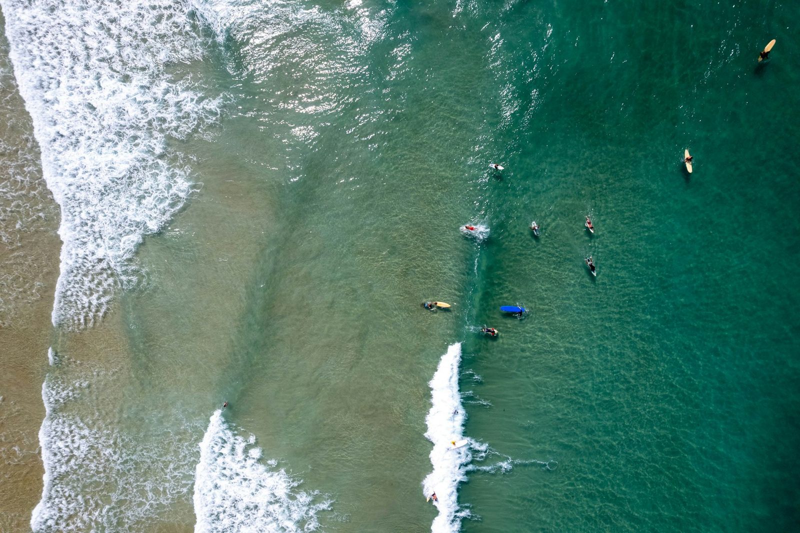 Aerial view of clean waves breaking along the sand at Duli Beach